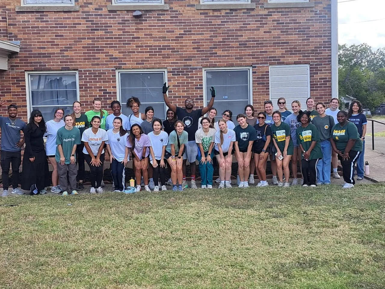 Moving team members posing with a group outside a brick building