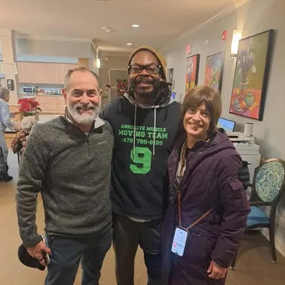 Moving team member standing with two people indoors