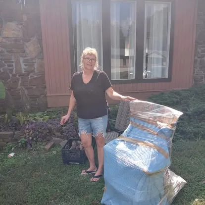 Woman standing beside wrapped furniture outside a home